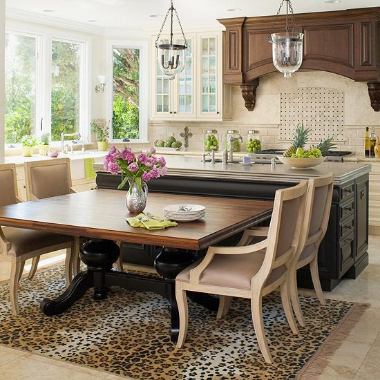 a dining room table and chairs in a large kitchen with white cabinets, leopard print area rug and chandelier hanging from the ceiling