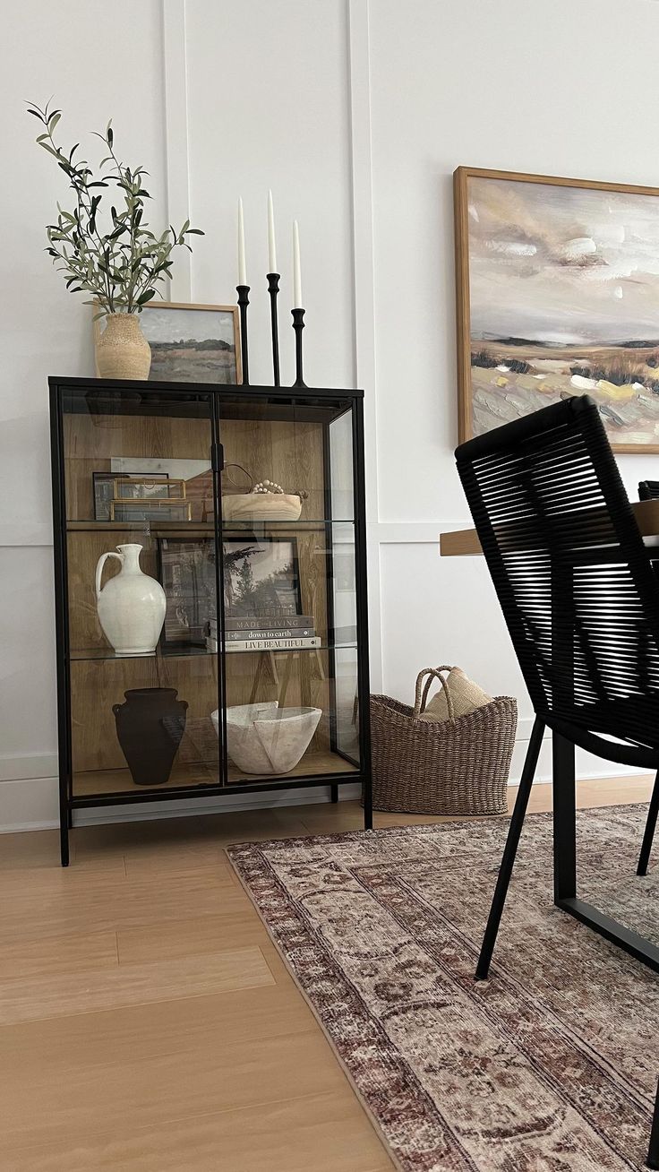 a dining room table and chairs with vases on display in front of the glass cabinet