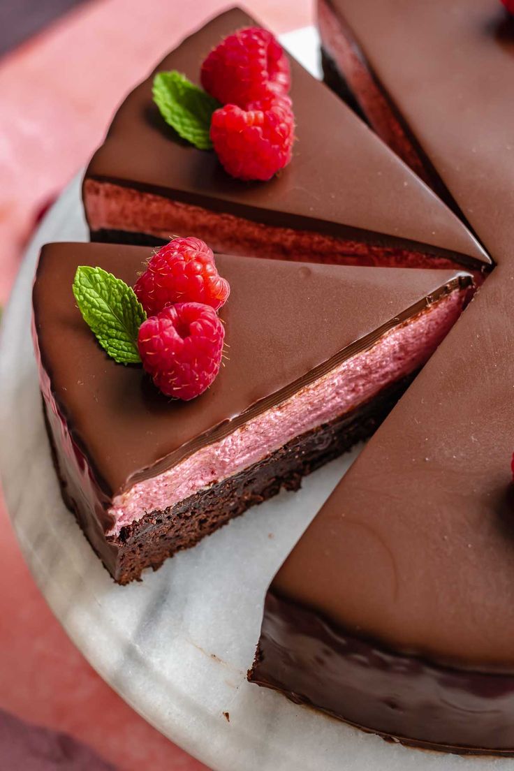 a chocolate cake topped with raspberries on top of a white plate