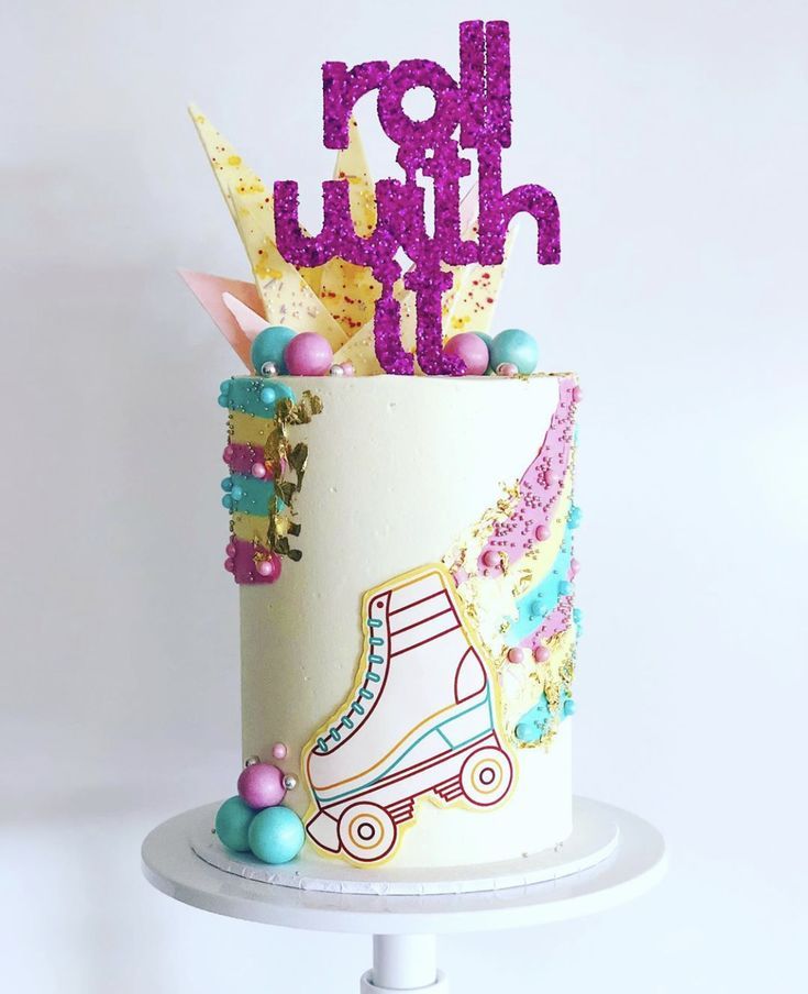 a birthday cake decorated with ice skates and beads on a white pedestal, holding the word happy birthday