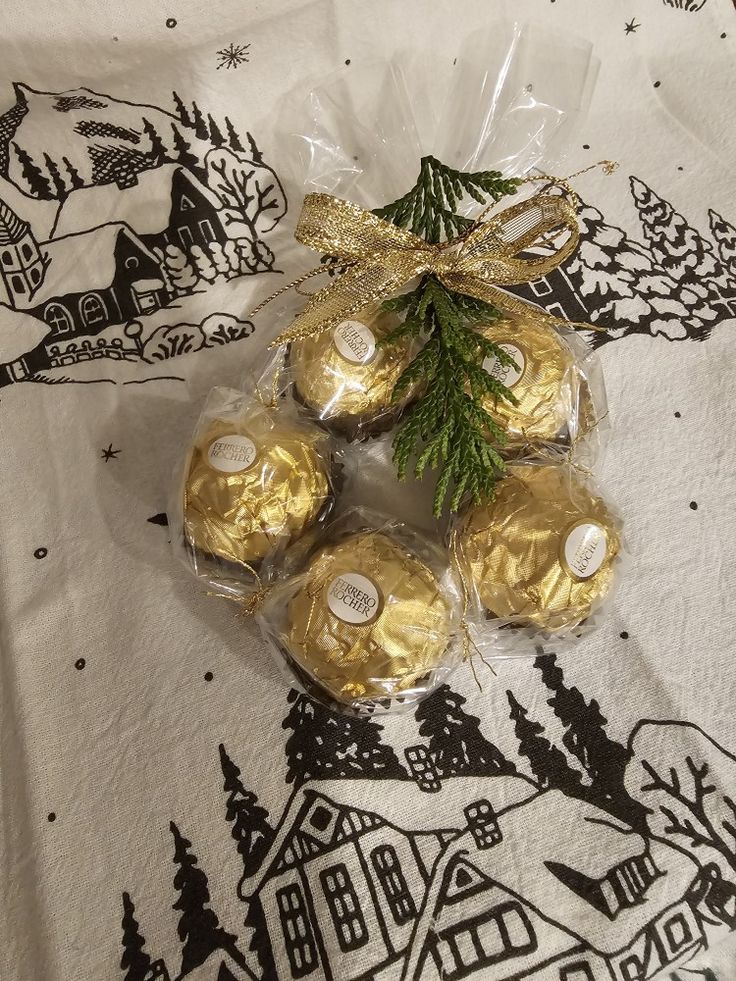 some chocolates wrapped in gold foil and tied with a ribbon on a white table cloth