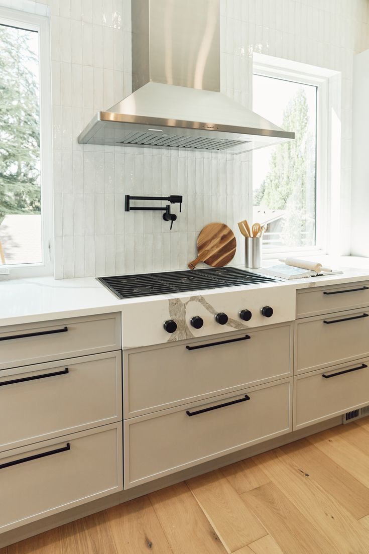 a stove top oven sitting inside of a kitchen next to a window and wooden floors