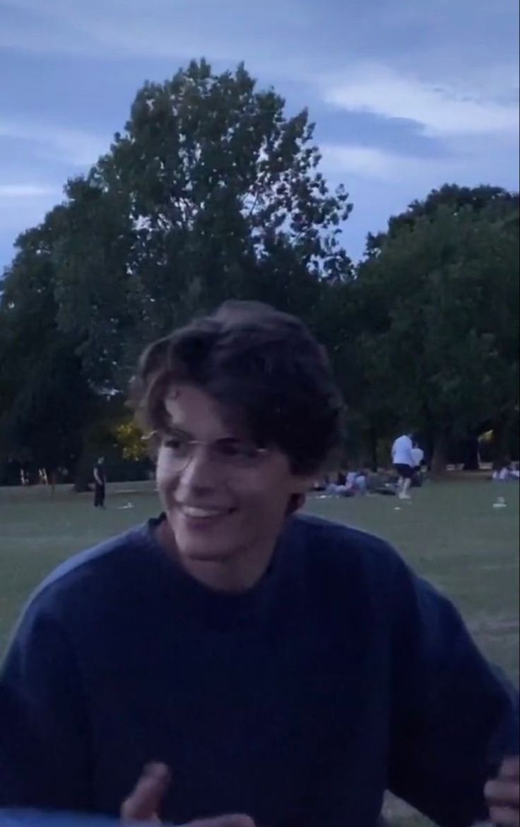 a young man holding a frisbee in his right hand and smiling at the camera