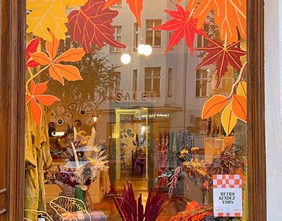 a store front window with autumn leaves painted on it