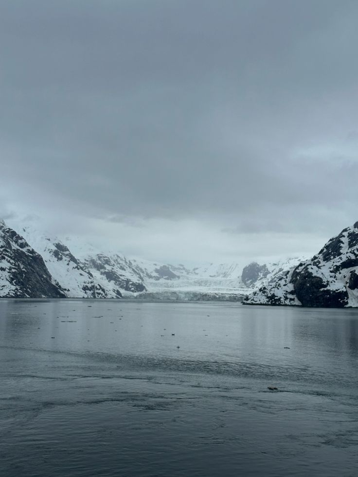 the mountains are covered in snow and ice as it sits on top of a body of water