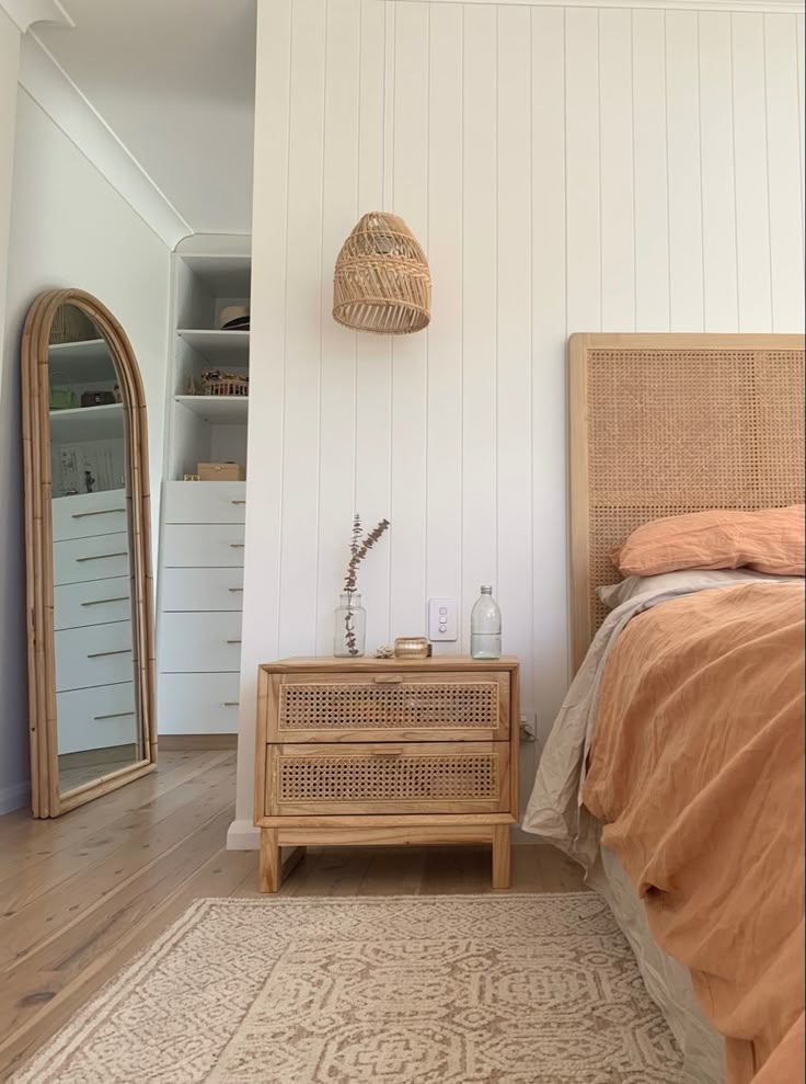 a bed room with a neatly made bed and a mirror on the wall next to it