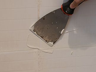 a person using a spatula to paint a brick wall with white paint on it