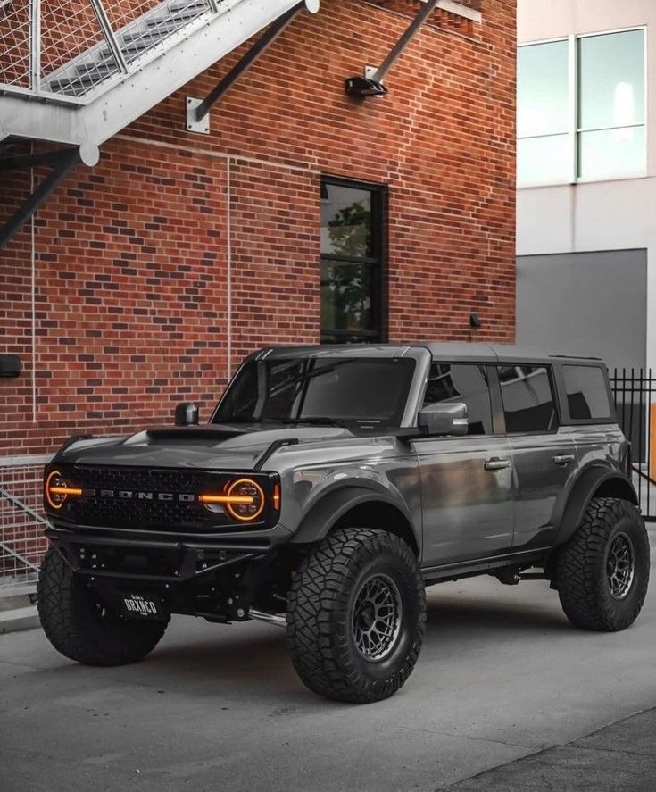 a black and silver truck parked in front of a brick building with stairs leading up to it