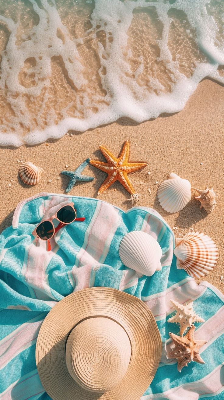 a beach towel, sunglasses and starfish on the sand