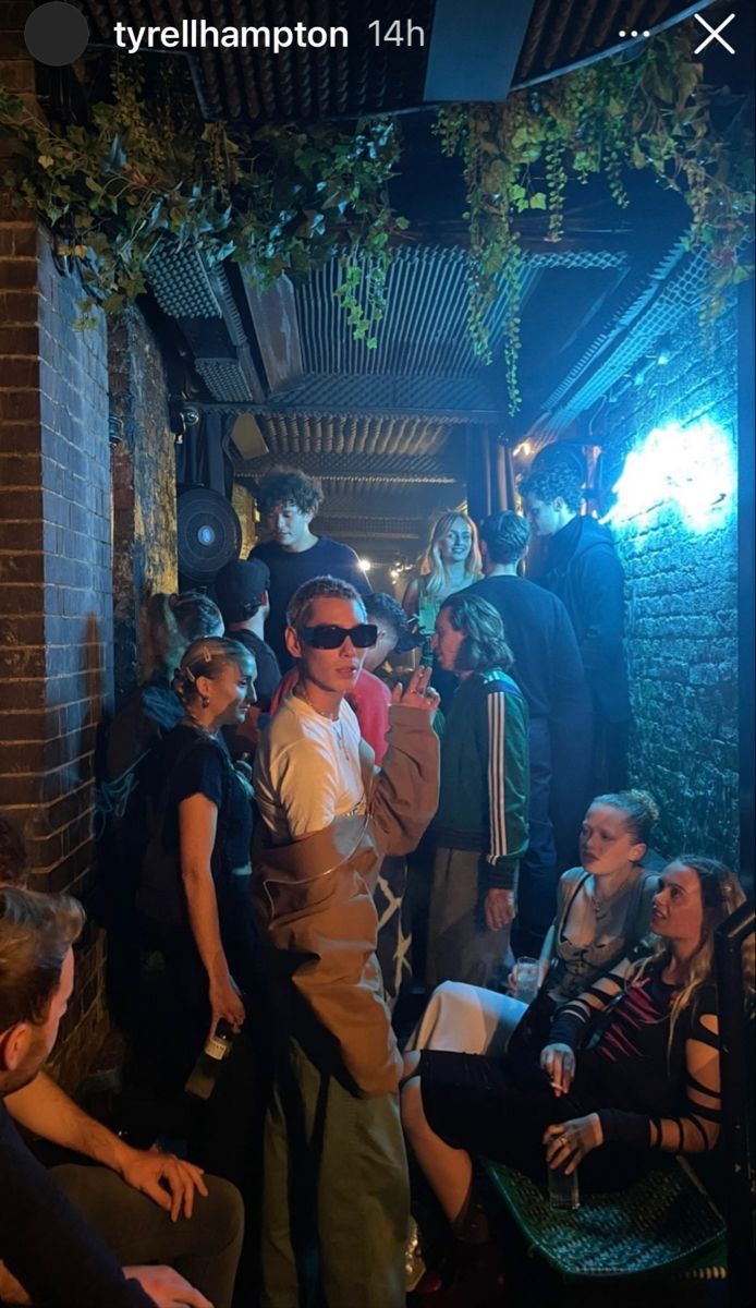 a group of people standing around each other in front of a brick building at night