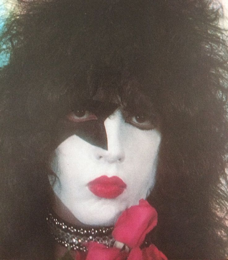 a woman with black hair and makeup holding a red rose