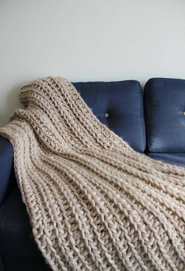 a blue couch with a knitted blanket on it