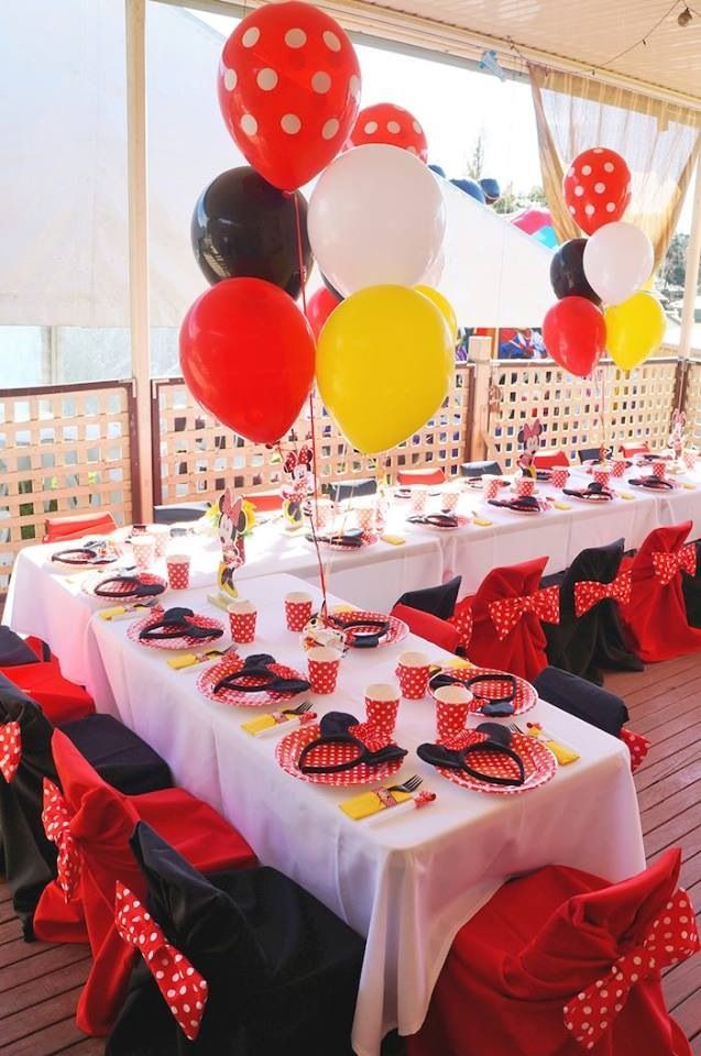 a table topped with lots of red and white balloons next to tables covered in black and white cloths