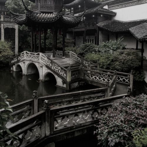 a bridge over a body of water surrounded by trees and buildings in the middle of it