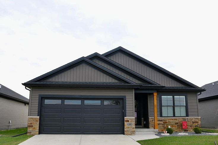 a gray house with two garages in the front and one on the other side