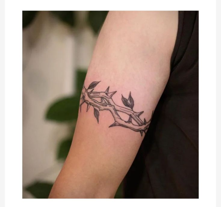 a tattoo on the arm of a woman with barbed wire and leaves around her neck