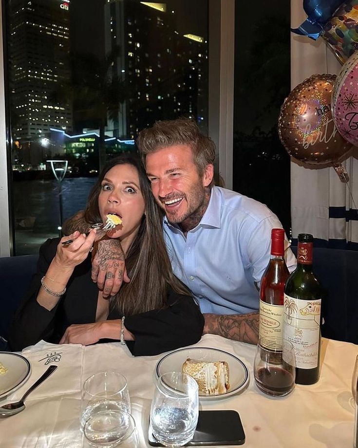 a man and woman sitting at a table eating cake