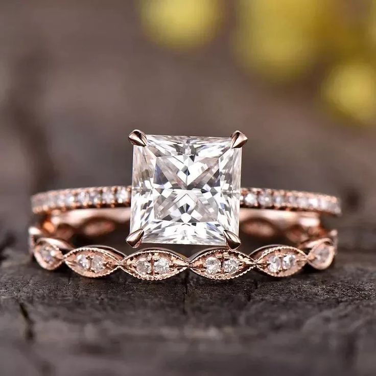 an engagement ring set with a princess cut diamond in the center and side stones on each band