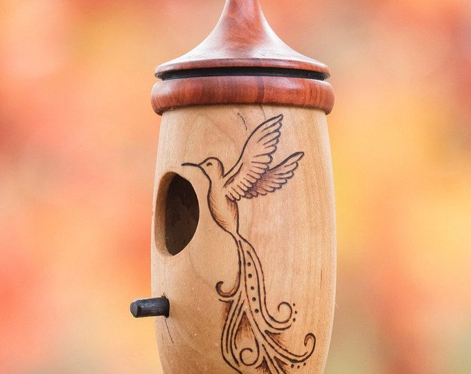 a wooden birdhouse with a hummingbird painted on it's side and an orange background