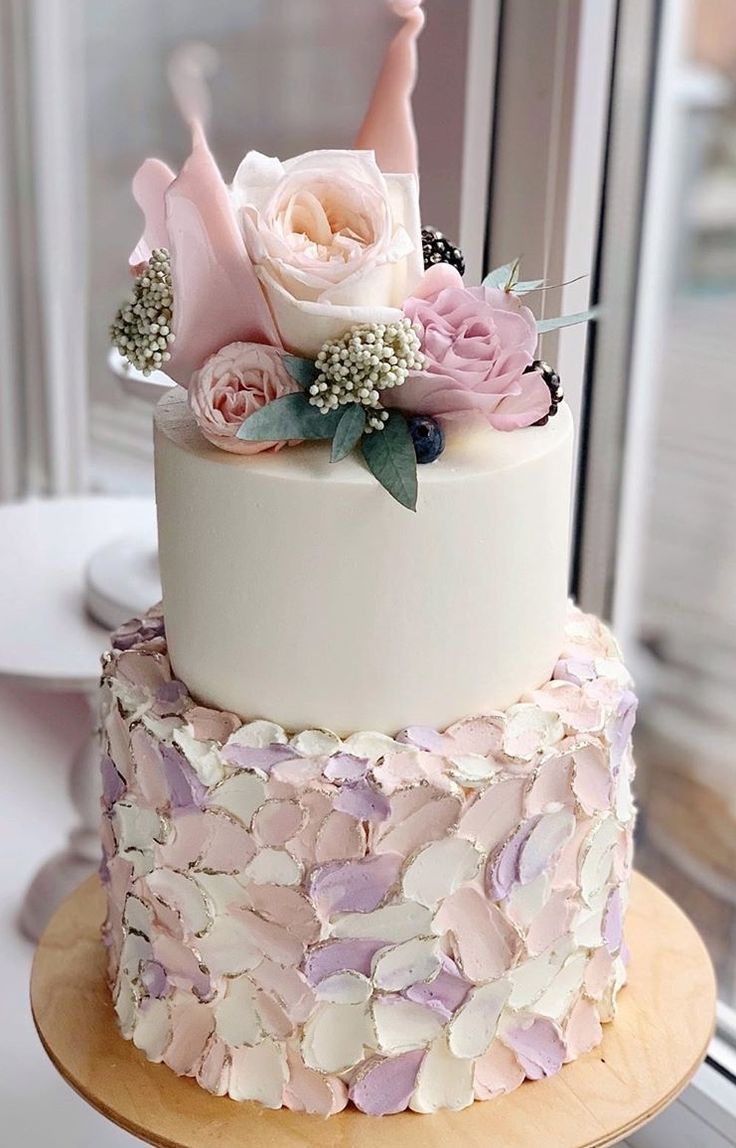 a white and pink wedding cake with flowers on top