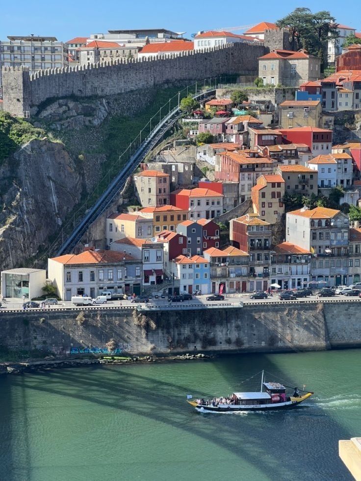 a small boat is in the water next to a city on a hill with many buildings