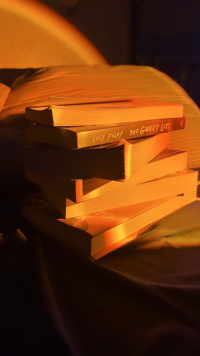 three books stacked on top of each other in front of a yellow light that is shining