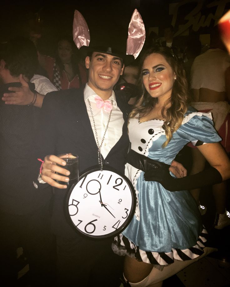 a man and woman dressed up in bunny ears pose for a photo while holding a clock