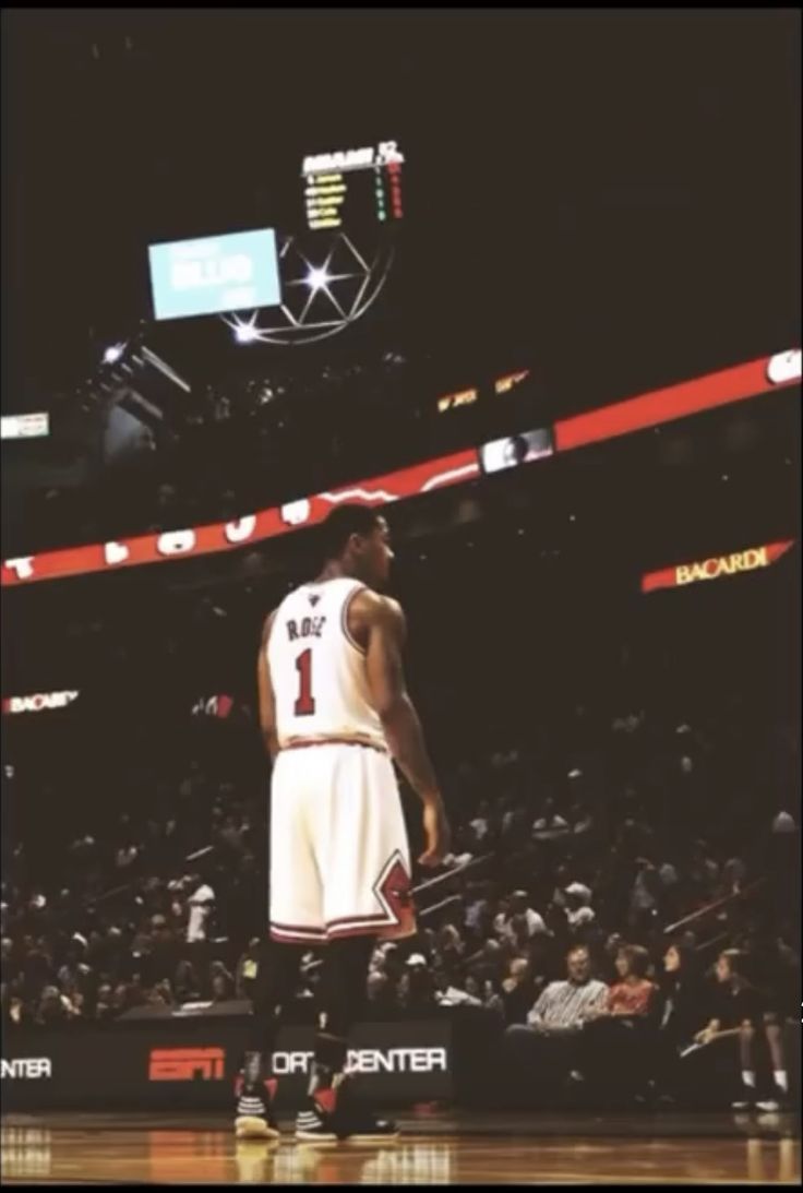 a basketball player is standing on the court in front of an arena full of fans