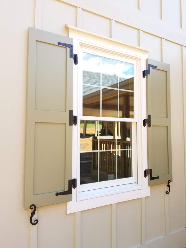 an open window on the side of a white building with black metal bars and brackets