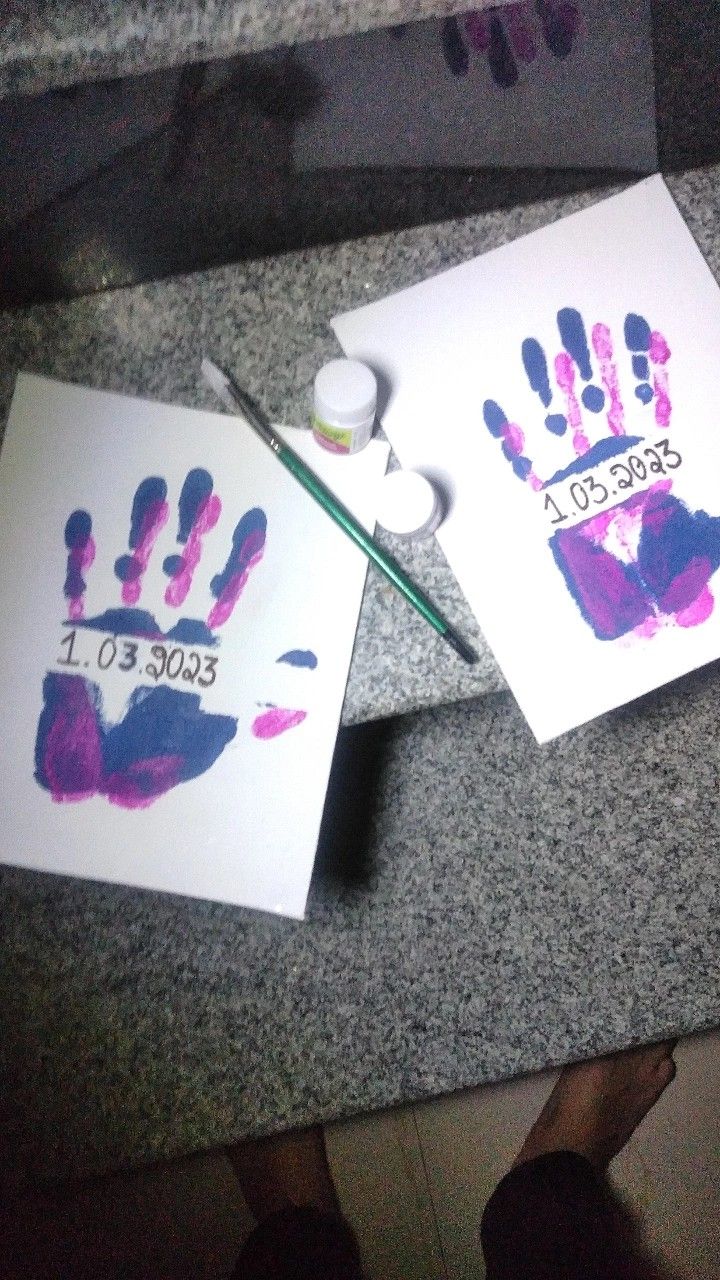 two handprints on white paper with purple and blue ink, one is for someone's hand