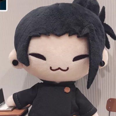 a stuffed doll with black hair sitting at a desk