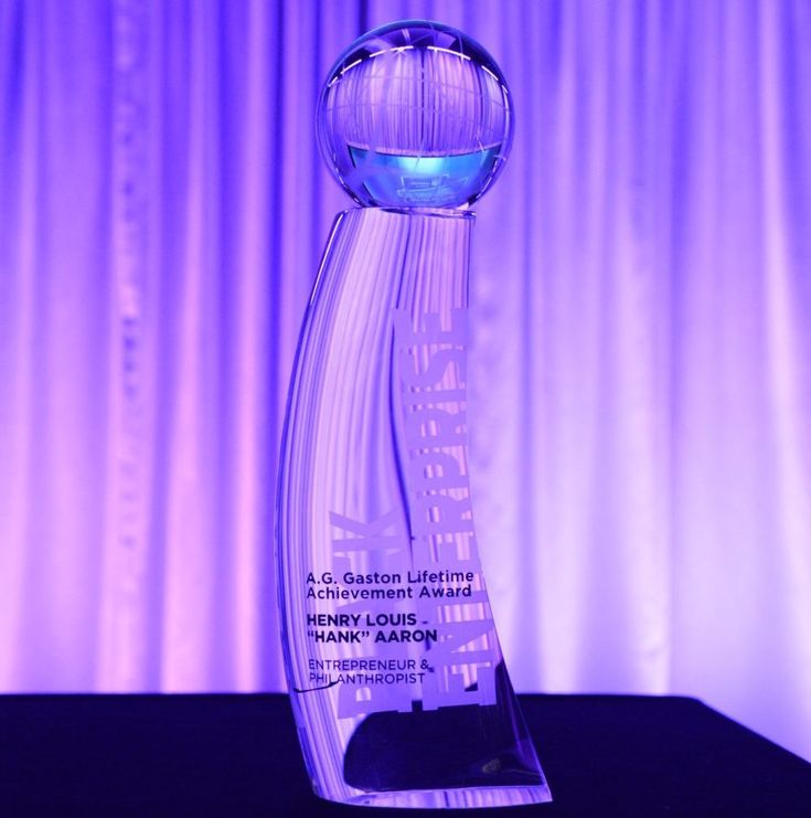 an award is displayed on a table in front of a purple curtained wall and drapes