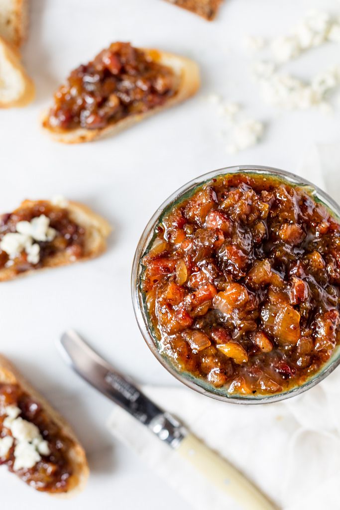 a glass jar filled with food sitting on top of a white table next to crackers