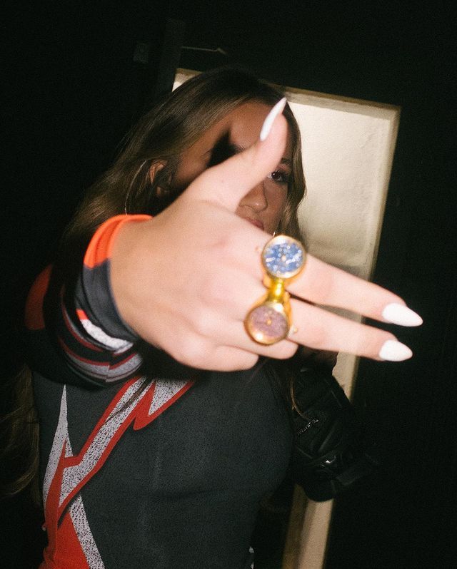 a woman pointing at the camera with her finger in front of her and wearing a ring