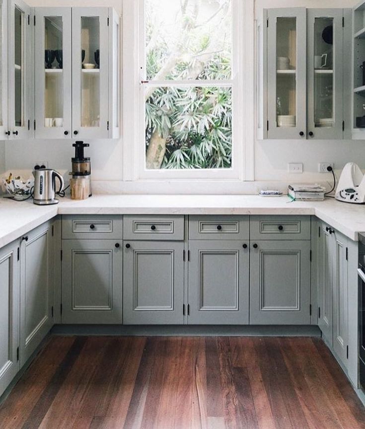 a kitchen with gray cabinets and white counter tops