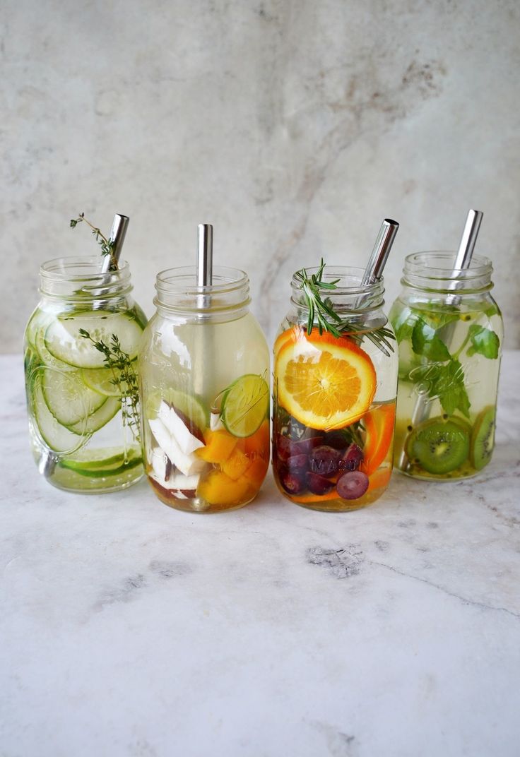 four mason jars filled with different types of fruits and vegetables