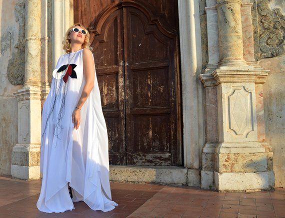 a woman standing in front of an old church door wearing a white dress and sunglasses