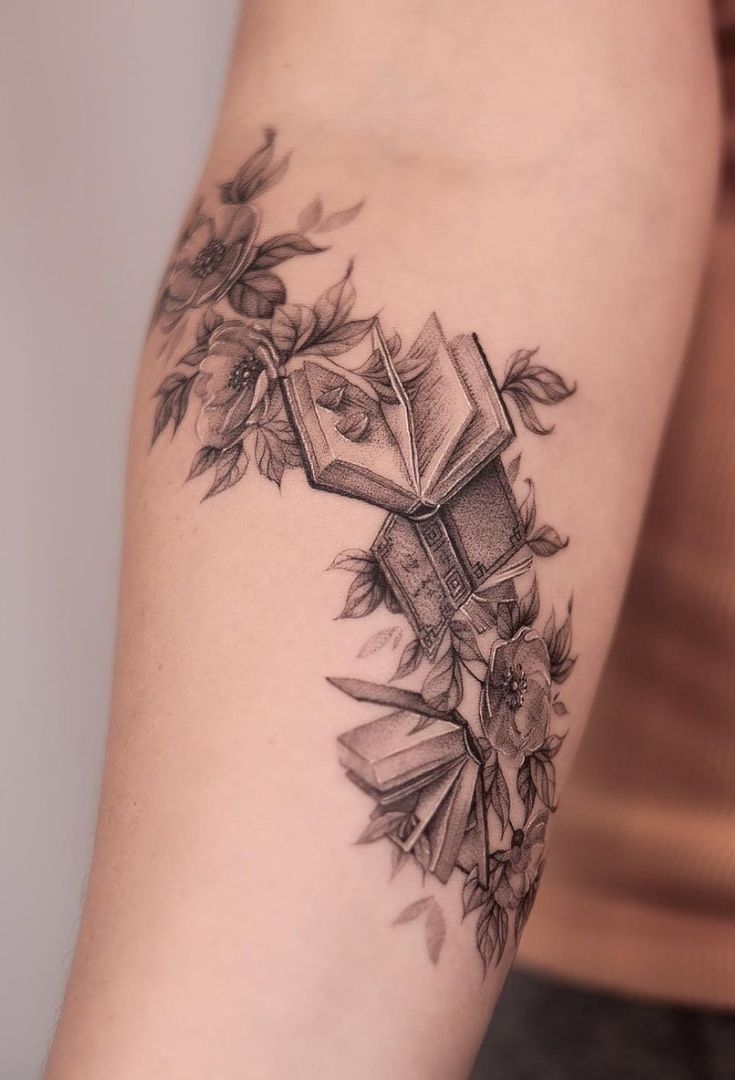 a woman's arm with an open book and flowers tattoo on her left arm