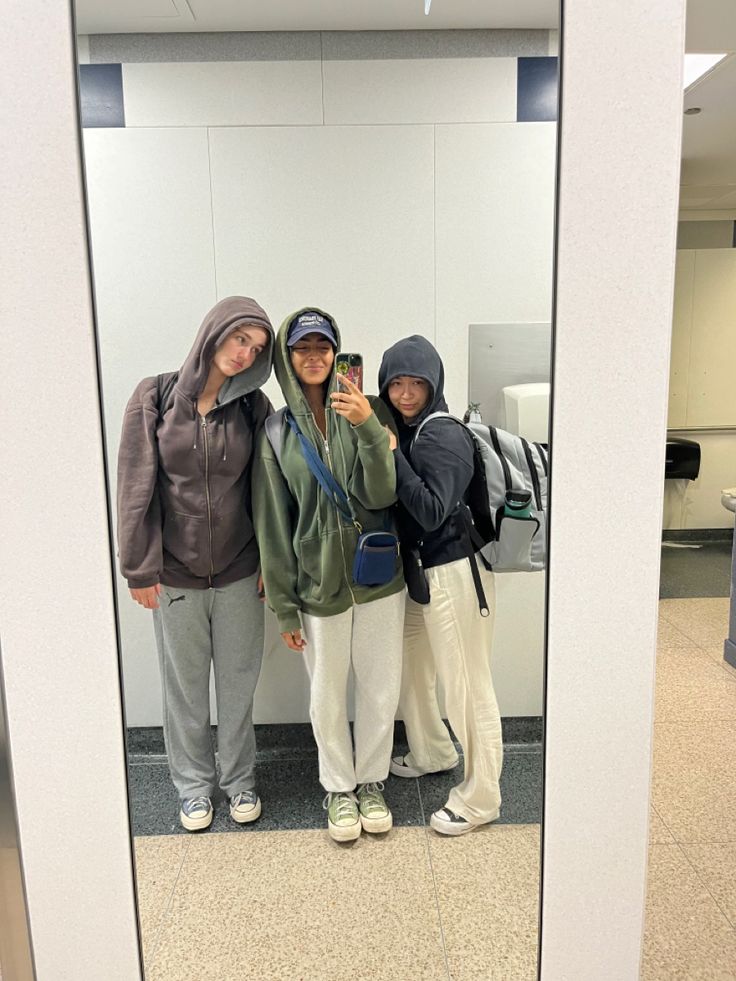 three people standing in front of a mirror taking a selfie