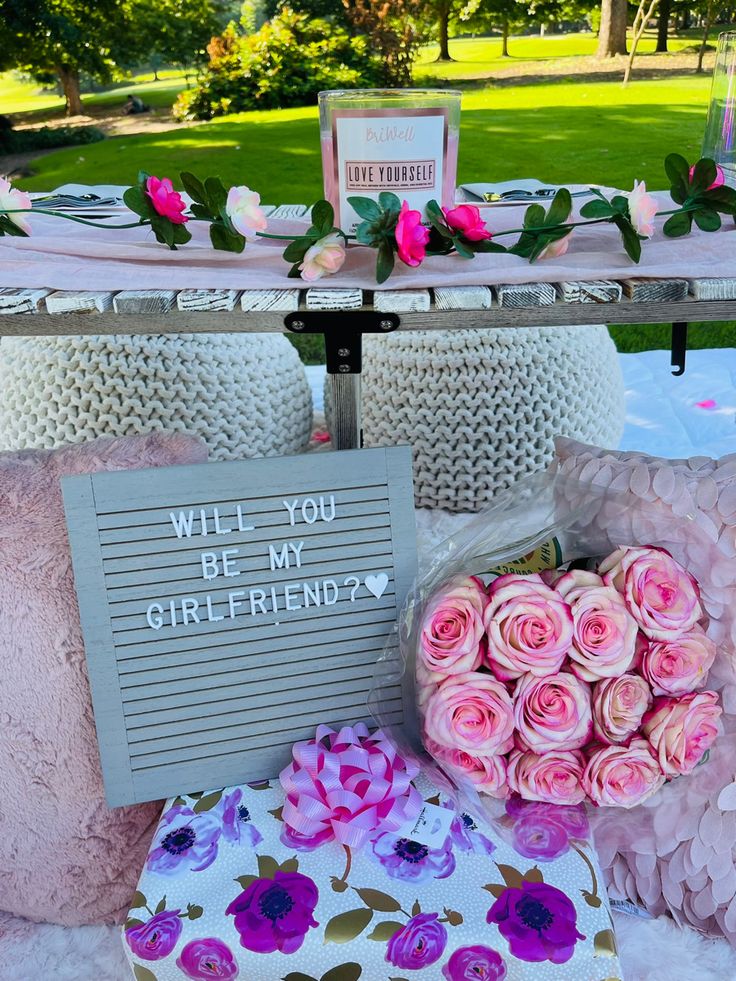 a table with pink flowers and a sign that says will you be my girlfriend?