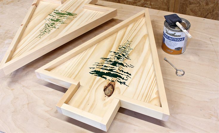 two wooden trays with pine trees on them next to a paintbrush and brush