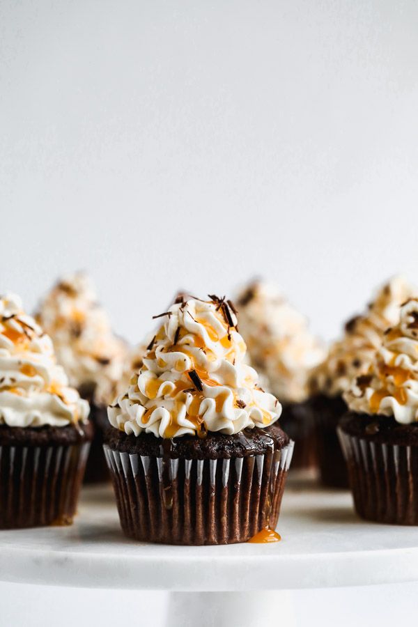 chocolate cupcakes topped with whipped cream and caramel drizzle