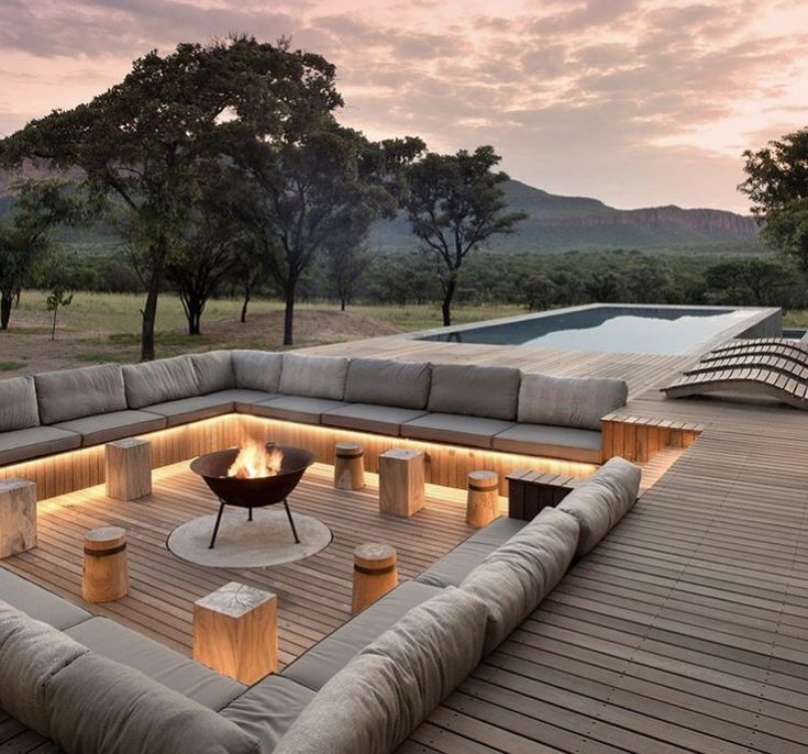 a large couch sitting on top of a wooden floor next to a swimming pool at sunset