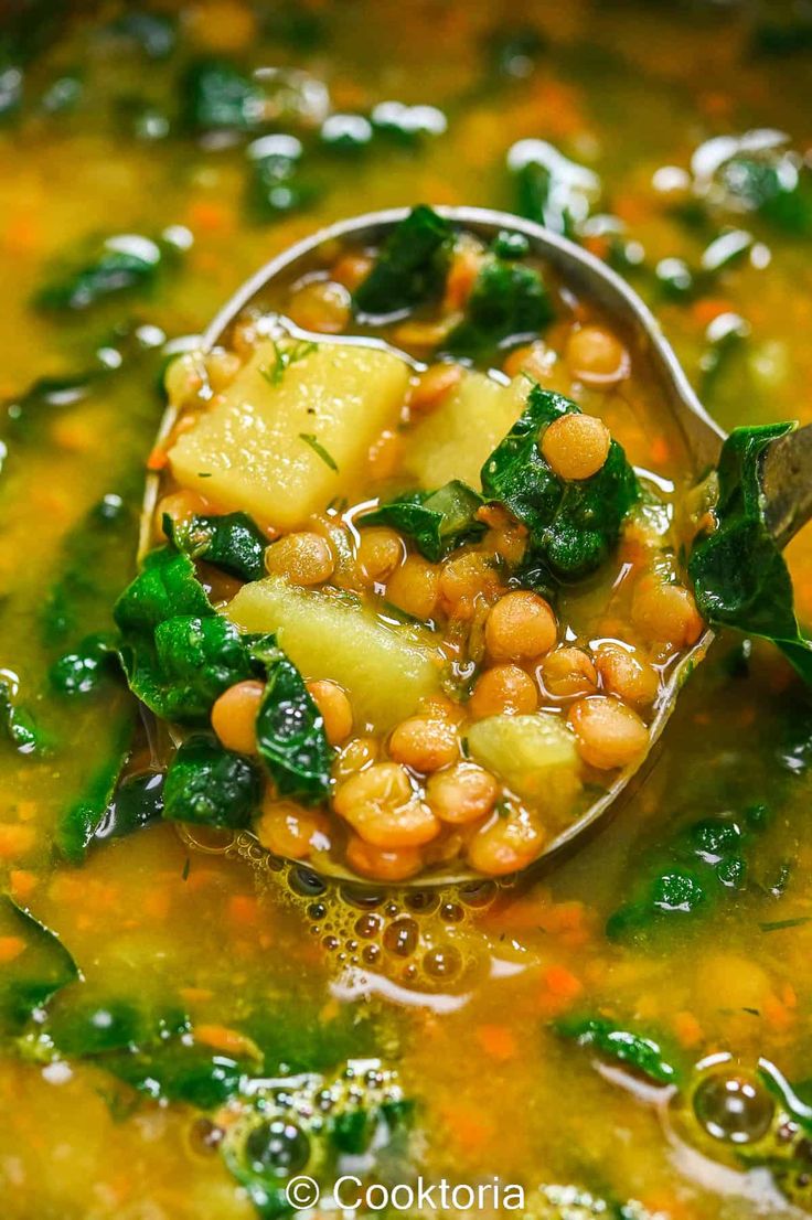 a spoon full of soup with spinach, pineapples and chickpeas