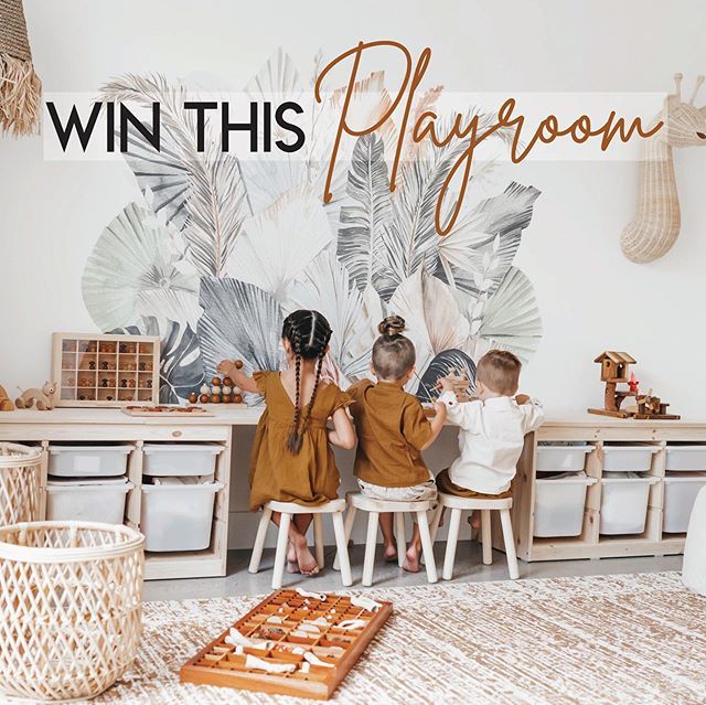 two children sitting on stools in front of a playroom with palm leaf wallpaper