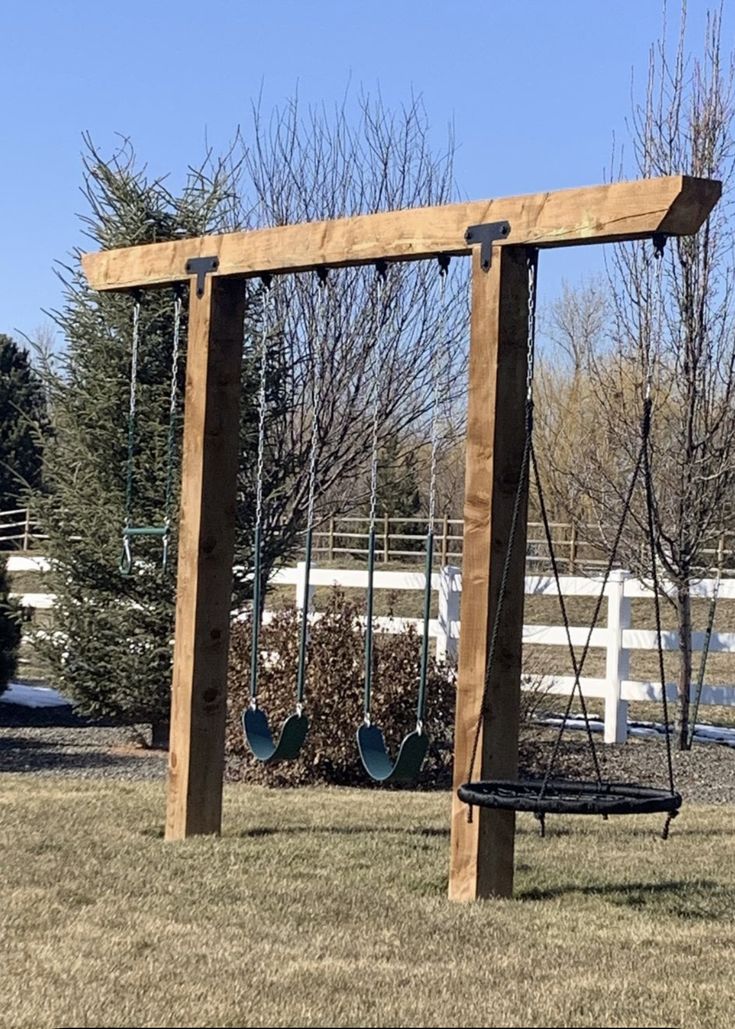 a wooden swing set with swings in the grass