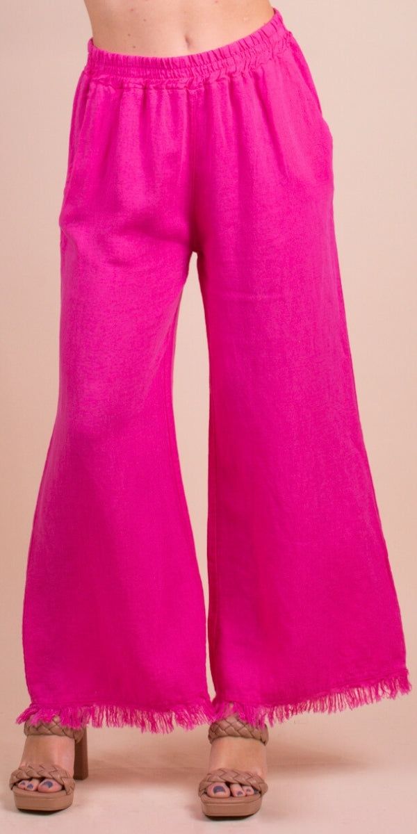 the woman is wearing bright pink pants with fringes on her legs and one hand in her pocket