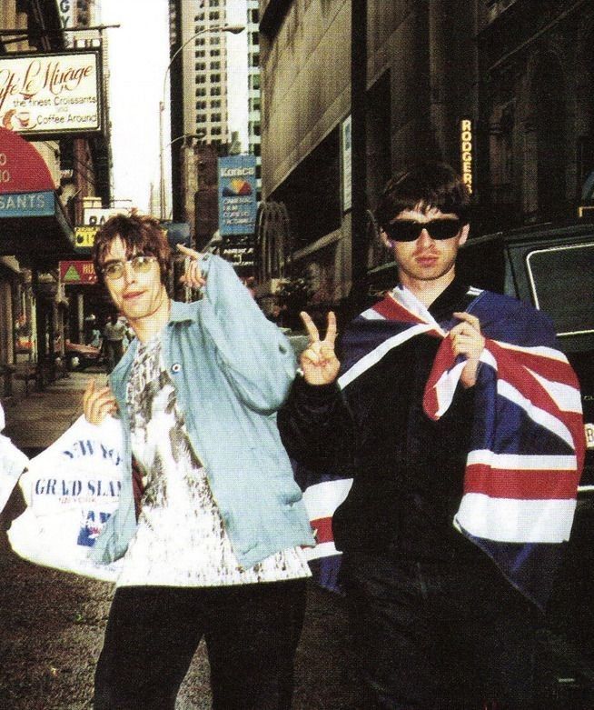 two young men walking down the street with their arms in the air and one holding an union jack flag