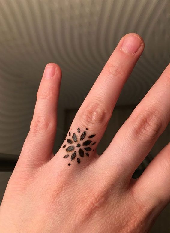 a person's hand with a small tattoo on the middle of their ring finger