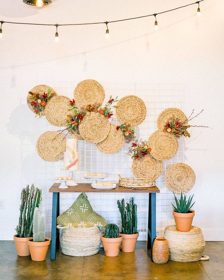 a table with baskets and potted plants next to a wall hanging on the wall